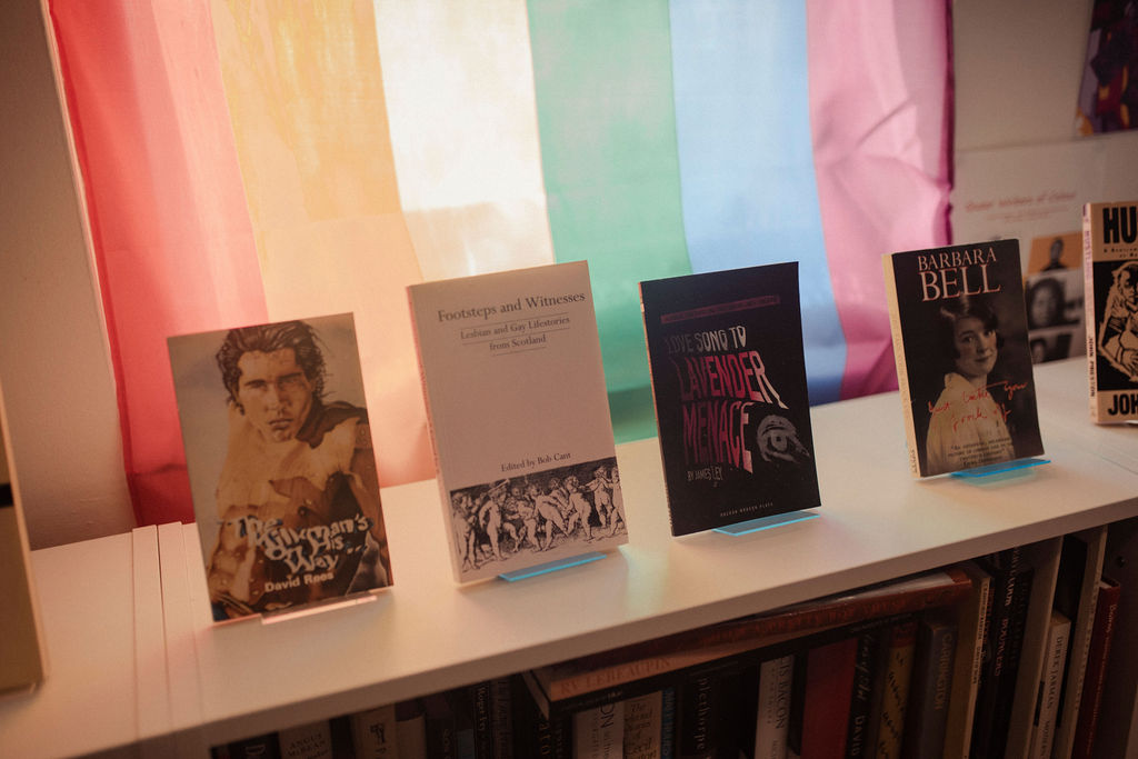 Photos of books in front of a rainbow pride flag